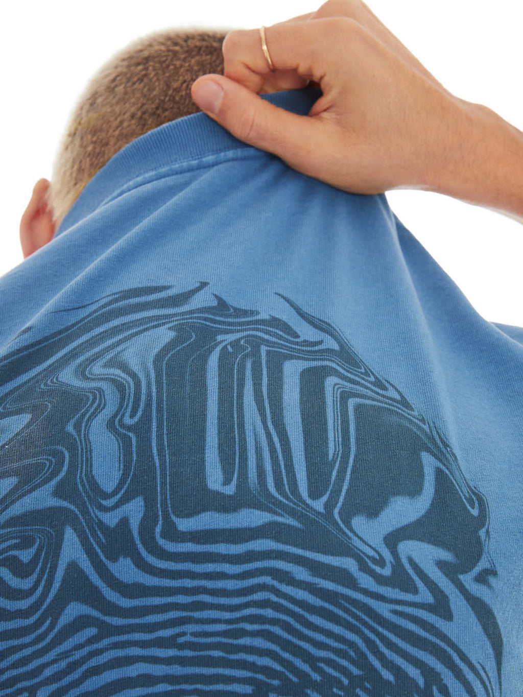 detail of model holding a blue t-shirt with fingerprint print