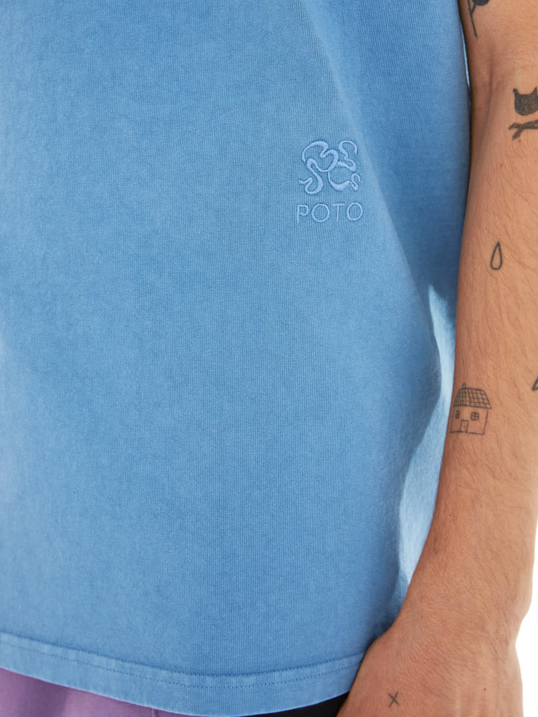 detail of model with blue t-shirt with tonal embroided monogram
