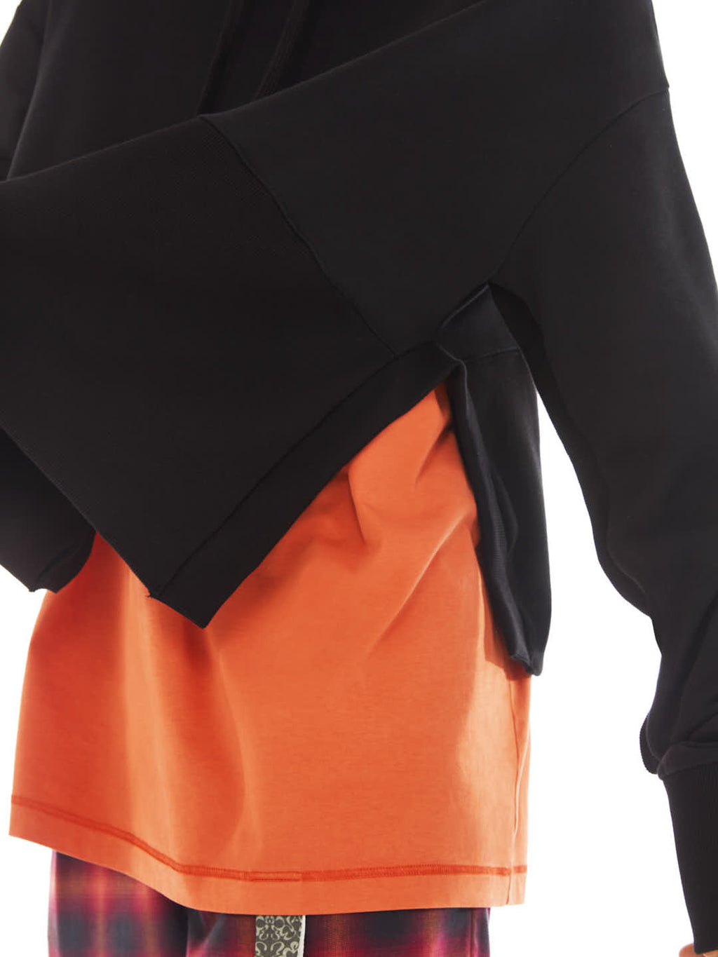detail of black poncho with maxi slit on the side with orange t-shirt under